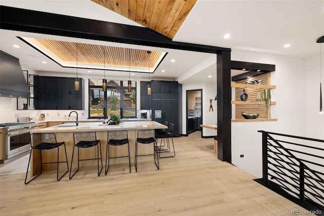 2800 Honors Ct, Silverthorne, CO 80498 - kitchen with stainless steel stove, light countertops, a breakfast bar, dark cabinetry, and light wood-type flooring