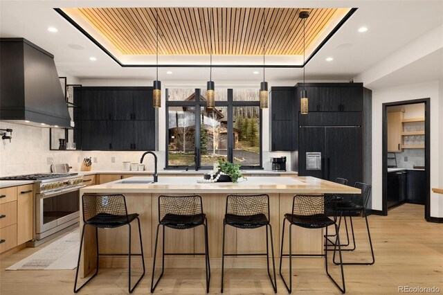 2800 Honors Ct, Silverthorne, CO 80498 - kitchen with high end stainless steel range oven, premium range hood, dark cabinetry, a raised ceiling, and modern cabinets