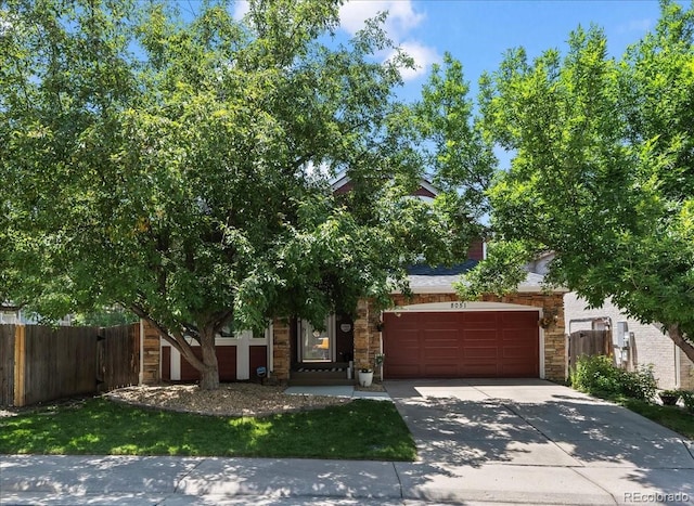 8051 W 78th Cir, Arvada, CO 80005 - view of property hidden behind natural elements with stone siding, concrete driveway, and an attached garage