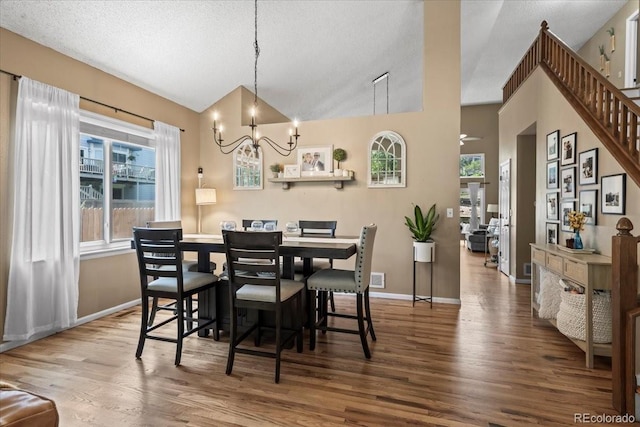 8051 W 78th Cir, Arvada, CO 80005 - dining space featuring a chandelier, wood finished floors, lofted ceiling, a textured ceiling, and stairs