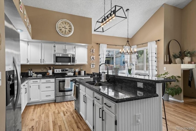 8051 W 78th Cir, Arvada, CO 80005 - kitchen featuring stainless steel appliances, a chandelier, a textured ceiling, white cabinetry, and light wood finished floors