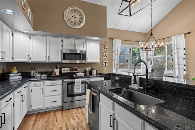 8051 W 78th Cir, Arvada, CO 80005 - kitchen with stainless steel appliances, lofted ceiling, a textured ceiling, white cabinets, and a chandelier