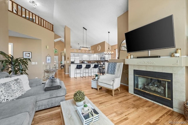 8051 W 78th Cir, Arvada, CO 80005 - living area with high vaulted ceiling, light wood-style floors, a chandelier, and a tiled fireplace
