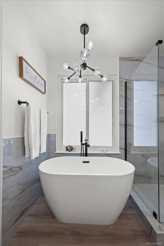8051 W 78th Cir, Arvada, CO 80005 - full bathroom featuring a chandelier, a freestanding tub, a shower stall, wood finished floors, and tile walls