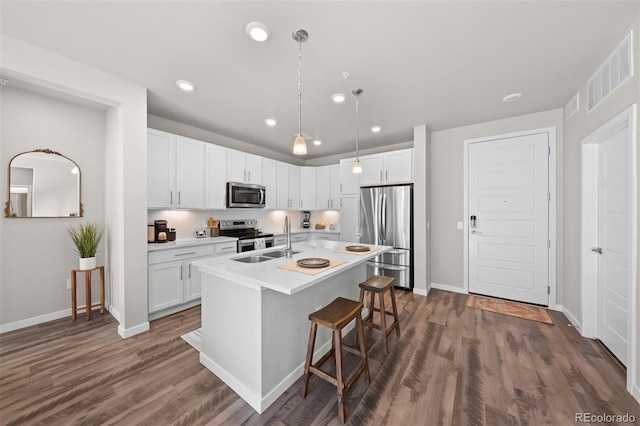 kitchen with dark hardwood / wood-style flooring, white cabinets, an island with sink, and appliances with stainless steel finishes