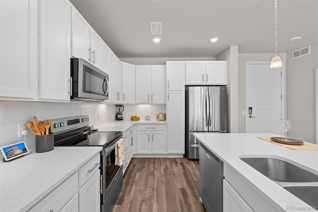 kitchen featuring stainless steel appliances, dark hardwood / wood-style flooring, backsplash, decorative light fixtures, and white cabinets