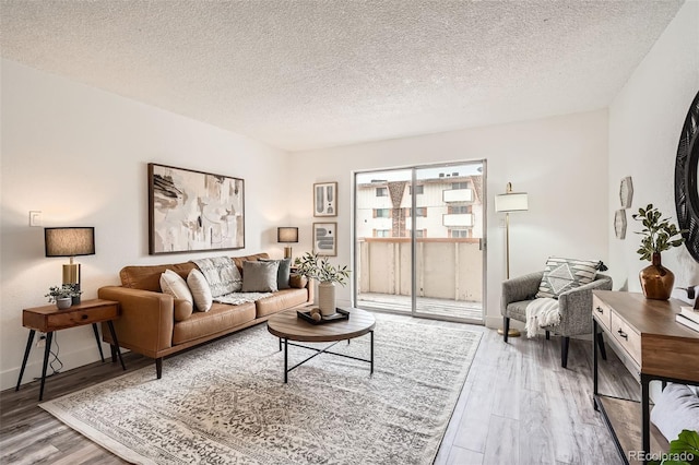 living area featuring a textured ceiling, wood finished floors, and baseboards