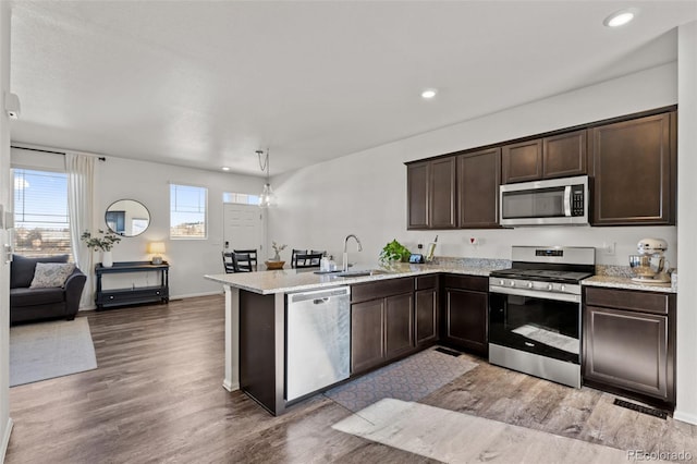 kitchen featuring dark brown cabinetry, stainless steel appliances, kitchen peninsula, and sink