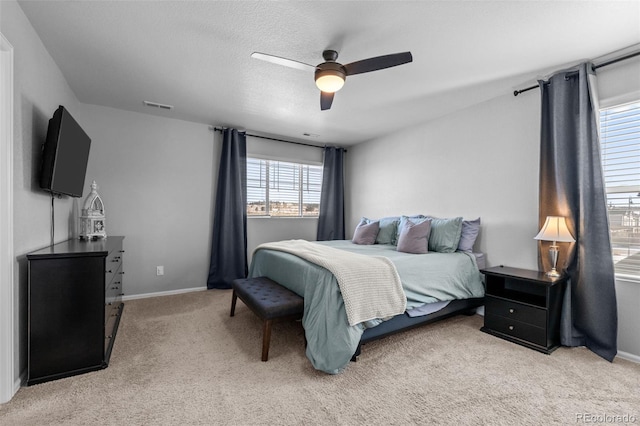 bedroom with ceiling fan, light colored carpet, and a textured ceiling