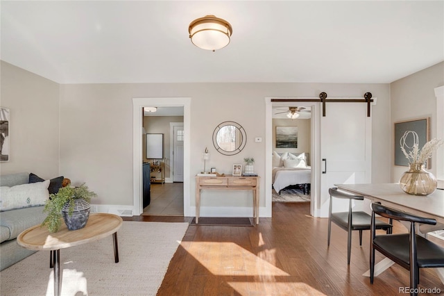 living room with a barn door, baseboards, and wood finished floors