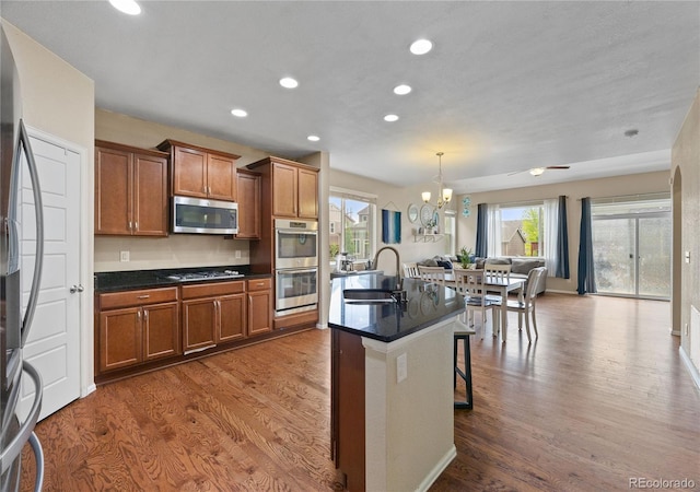 41 Jordan Ln, Erie, CO 80516 - kitchen featuring stainless steel appliances, a sink, brown cabinetry, dark countertops, and recessed lighting
