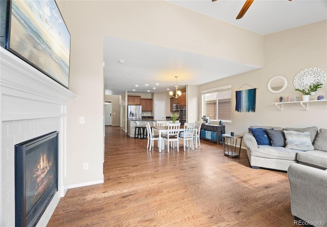41 Jordan Ln, Erie, CO 80516 - living room featuring a ceiling fan, a chandelier, a glass covered fireplace, light wood-style floors, and recessed lighting