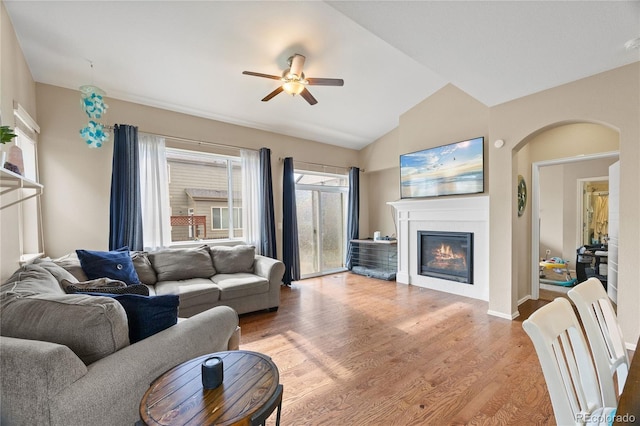 41 Jordan Ln, Erie, CO 80516 - living area featuring ceiling fan, a glass covered fireplace, lofted ceiling, light wood finished floors, and arched walkways