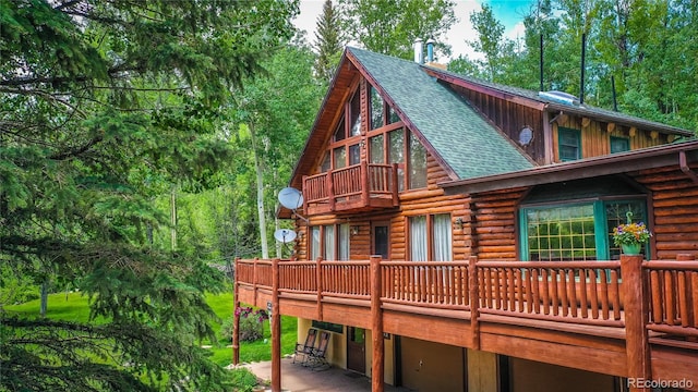 view of side of home featuring log exterior, a garage, and a shingled roof