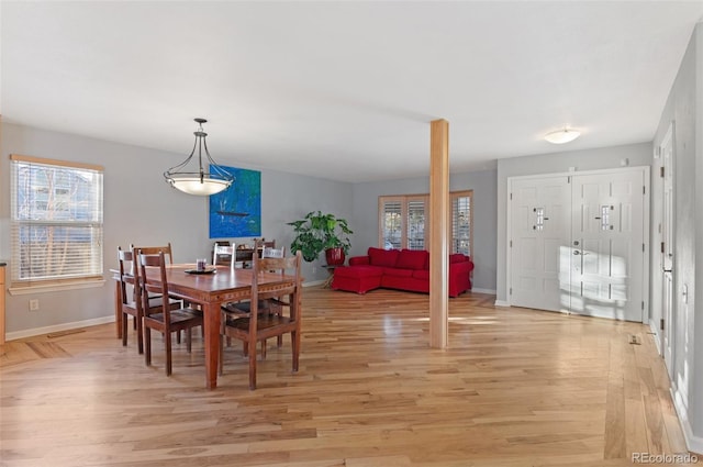 dining area with baseboards and light wood-style flooring