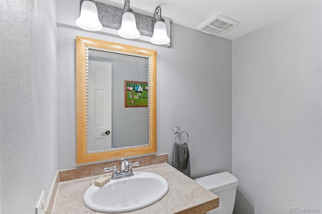 bathroom with visible vents, toilet, and vanity