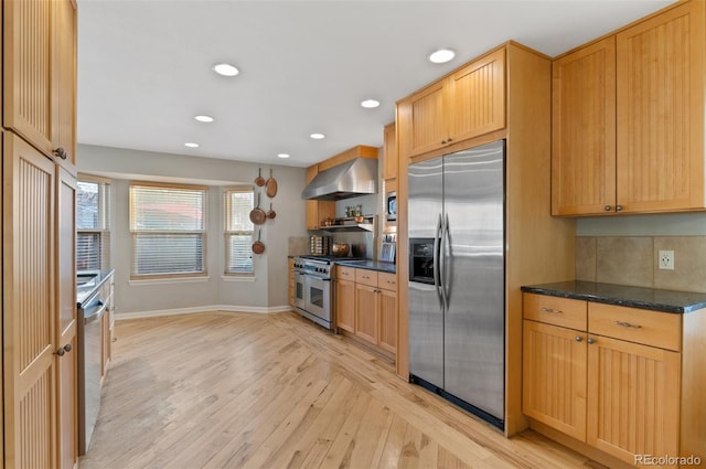 kitchen with baseboards, recessed lighting, appliances with stainless steel finishes, light wood-style floors, and wall chimney exhaust hood