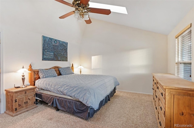 bedroom featuring vaulted ceiling with skylight, light colored carpet, baseboards, and ceiling fan