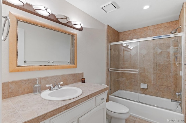 full bathroom with visible vents, bath / shower combo with glass door, vanity, and toilet