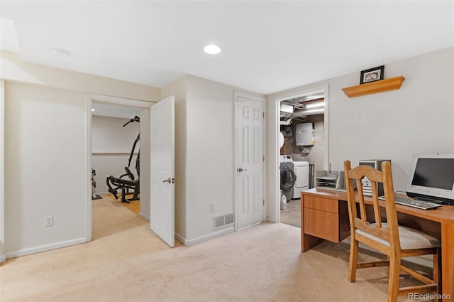 carpeted office space with visible vents, baseboards, separate washer and dryer, and water heater