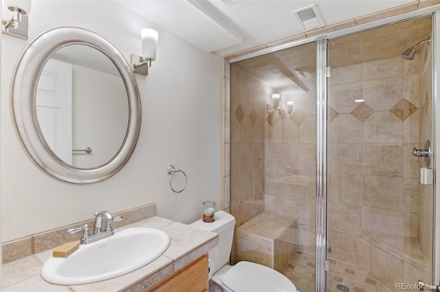 bathroom with vanity, a shower stall, toilet, and visible vents