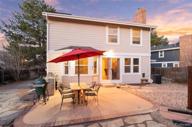 back of property featuring a patio, a fenced backyard, central AC, and a chimney