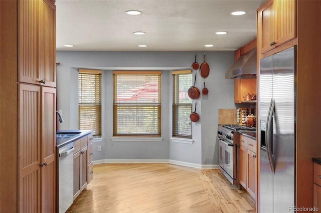 10200 Julian St, Westminster, CO 80031 - kitchen with wall chimney exhaust hood, dark countertops, stainless steel appliances, and light wood-style flooring