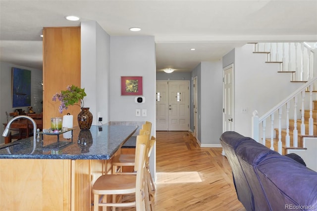 10200 Julian St, Westminster, CO 80031 - kitchen with recessed lighting, light wood finished floors, baseboards, dark stone counters, and a kitchen bar