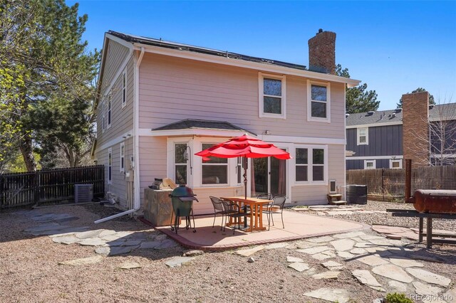 10200 Julian St, Westminster, CO 80031 - rear view of house featuring a fenced backyard, a chimney, central AC unit, and a patio