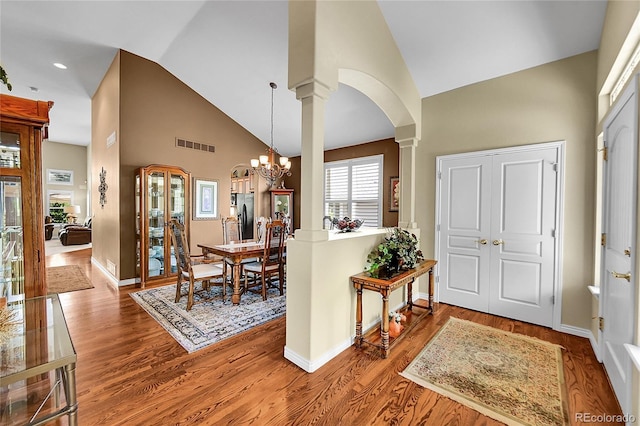 6696 S Quail Ct, Littleton, CO 80127 - entryway with arched walkways, high vaulted ceiling, decorative columns, wood finished floors, and a chandelier