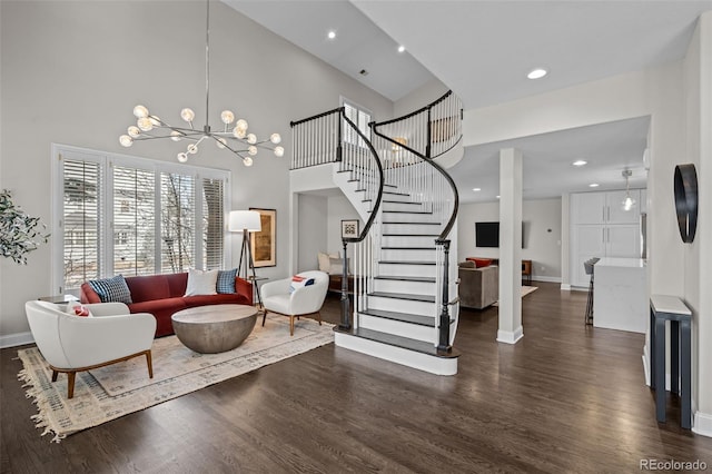 living room with dark hardwood / wood-style flooring, a towering ceiling, and a notable chandelier