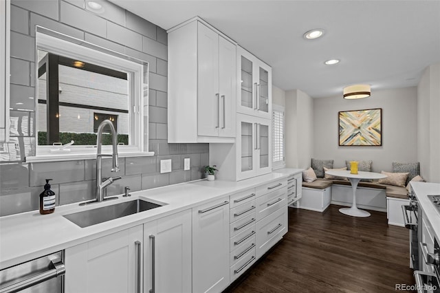 kitchen featuring white cabinets, breakfast area, tasteful backsplash, and sink