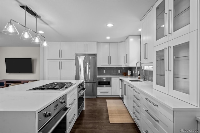 kitchen with pendant lighting, dark wood-type flooring, white cabinets, sink, and stainless steel appliances