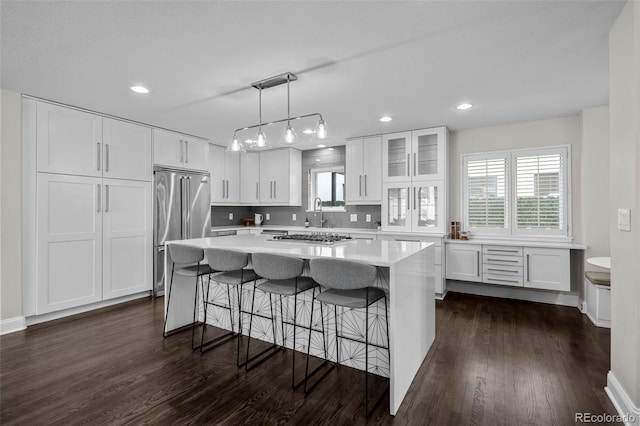 kitchen with decorative light fixtures, a center island, white cabinetry, and appliances with stainless steel finishes