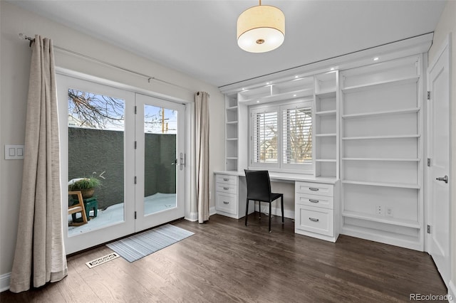 unfurnished office featuring dark hardwood / wood-style flooring and built in desk