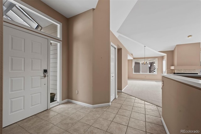 foyer with lofted ceiling, a chandelier, and light tile patterned floors