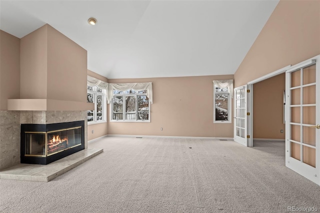 unfurnished living room featuring high vaulted ceiling, carpet floors, a fireplace, and french doors