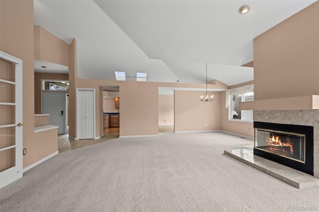 unfurnished living room with light carpet, a notable chandelier, a tiled fireplace, and high vaulted ceiling