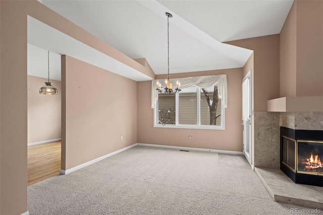 unfurnished dining area with an inviting chandelier, a tiled fireplace, vaulted ceiling, and light carpet