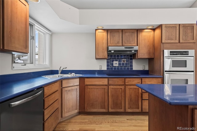 kitchen with appliances with stainless steel finishes, sink, light hardwood / wood-style floors, and decorative backsplash