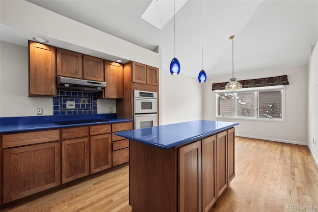 kitchen with cooktop, light hardwood / wood-style flooring, double oven, a kitchen island, and pendant lighting