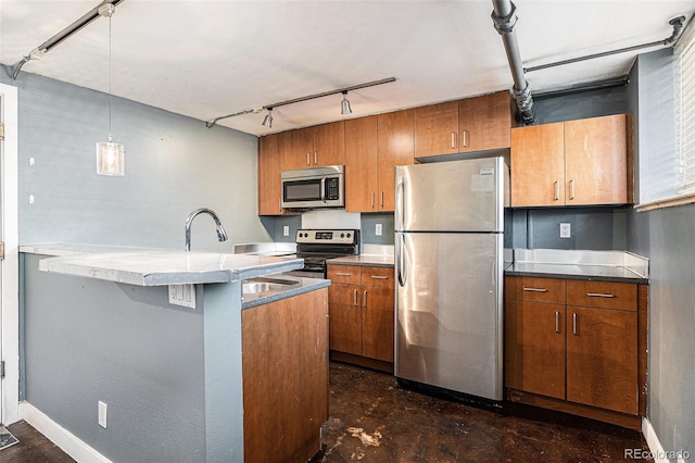 500 E 11th Ave Unit 102, Denver, CO 80203 - kitchen featuring appliances with stainless steel finishes, track lighting, brown cabinets, decorative light fixtures, and baseboards