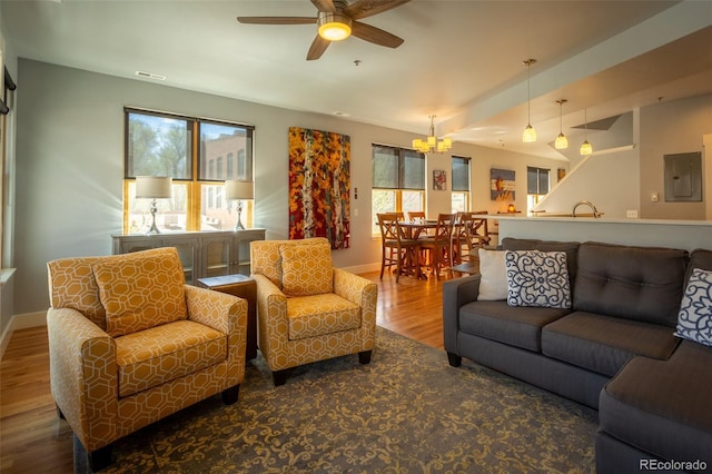 living room featuring baseboards, a wealth of natural light, electric panel, and wood finished floors