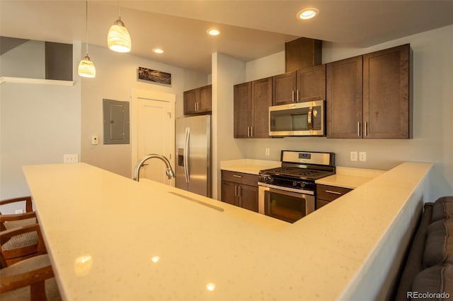 kitchen featuring dark brown cabinets, light countertops, a kitchen breakfast bar, stainless steel appliances, and electric panel