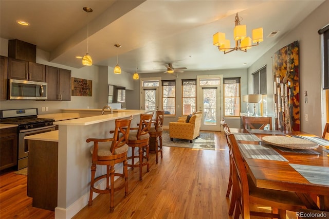 kitchen featuring light countertops, stainless steel appliances, pendant lighting, and light wood-style floors