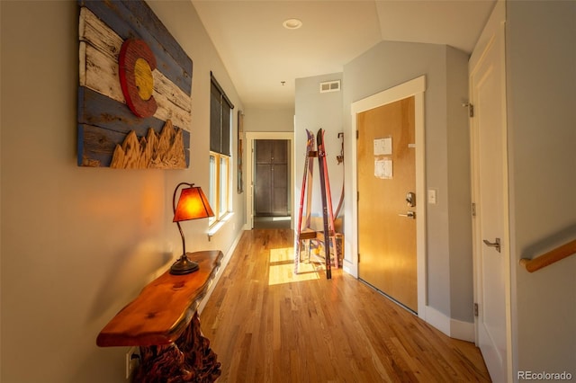 hallway featuring baseboards, lofted ceiling, wood finished floors, and visible vents