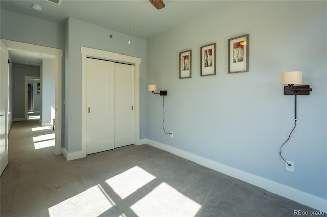 unfurnished bedroom featuring baseboards, carpet flooring, and a closet