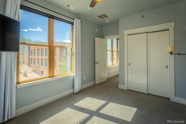 unfurnished bedroom with visible vents, carpet flooring, baseboards, and multiple windows