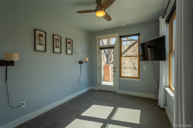 interior space with baseboards, ceiling fan, and visible vents