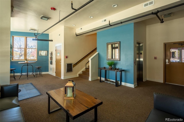 living area featuring visible vents, carpet, baseboards, and elevator